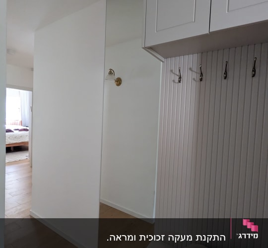 מראה על קיר ליד מתלה בגדים